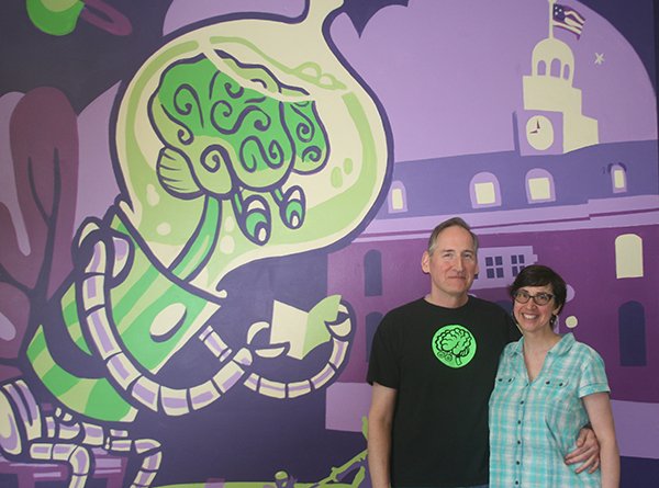 HFC alumni/Green Brain Comics co-owners Dan and Katie Merritt pose in front of their store's mural. 