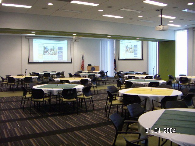 Inside of large room with rows of long, circular tables and a podium at the furthest end of the room