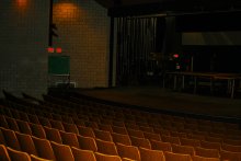 Photograph of inside of Adray Auditorium, with several rows of seats facing the stage that spans the width of the auditorium 
