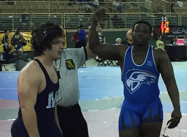 Jeffrey Henderson (right) has his arm raised in victory by referee. Henderson became the first All-American wrestler at HFC in March. 