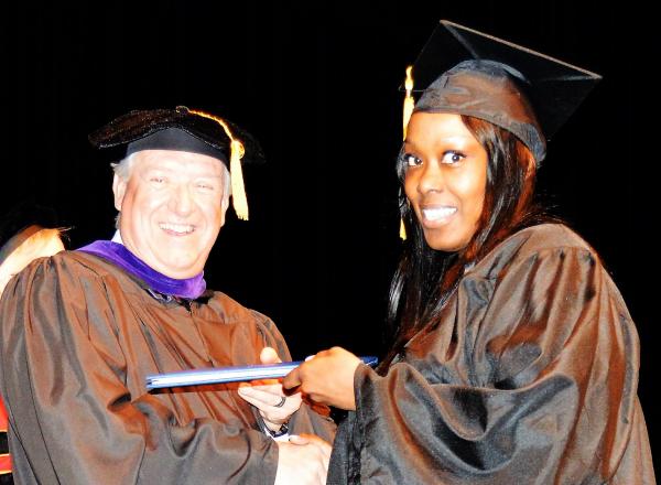 Interim President John Satkowski gives a graduate her diploma