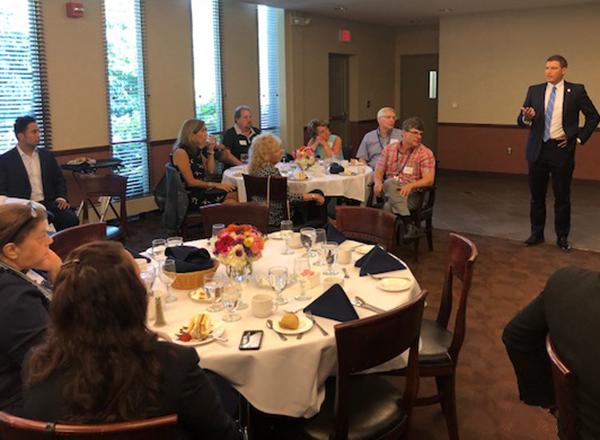President Kavalhuna stands and addresses seated group at a luncheon.