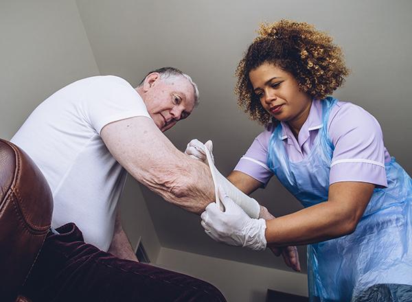Medical assistant wearing gloves pulls a compression sleeve onto a patient's arm