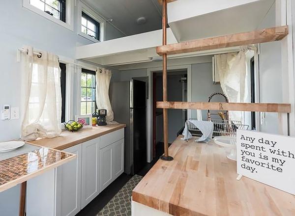 Interior of tiny house, all-white interior with loft, light wood butcher-block counters