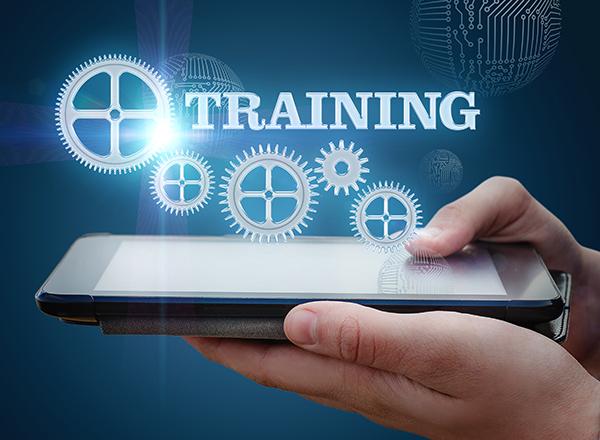 Hands holding a computer tablet face-up, with the word TRAINING and some holographic gears above the tablet
