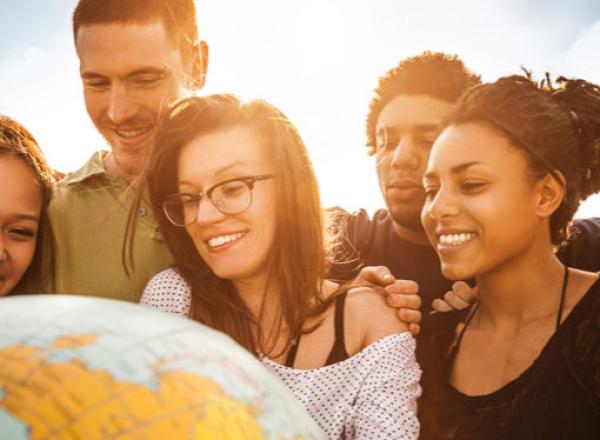 Diverse students facing a globe, smiling