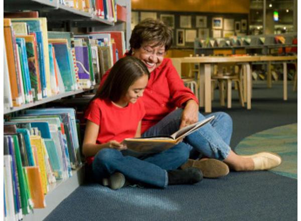 Photo of grandmother reading with her granddaughter in a library. From the Colorin Colorado website. 