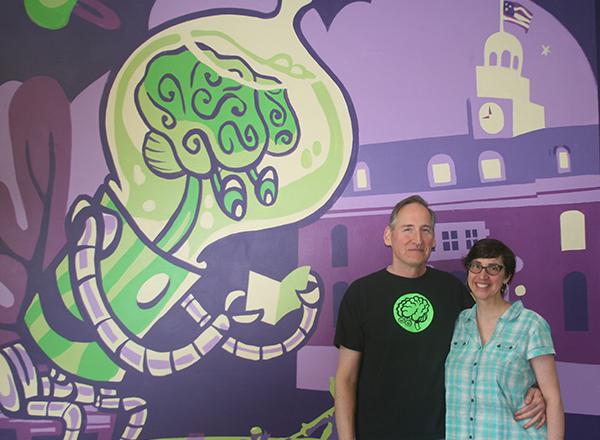HFC alumni/Green Brain Comics co-owners Dan and Katie Merritt pose in front of their store's mural. 