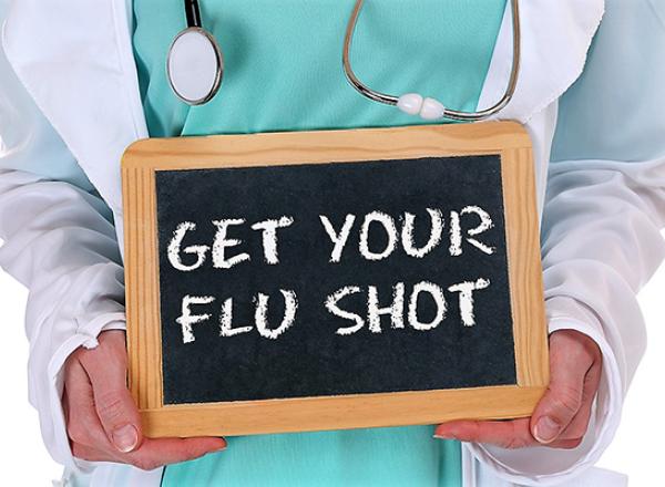 health care worker holding a sign with "Get Your Flu Shot"
