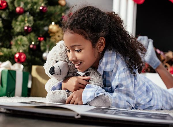 Child reading a book holding a teddy bear