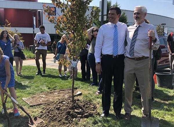 Two men standing next to a tree