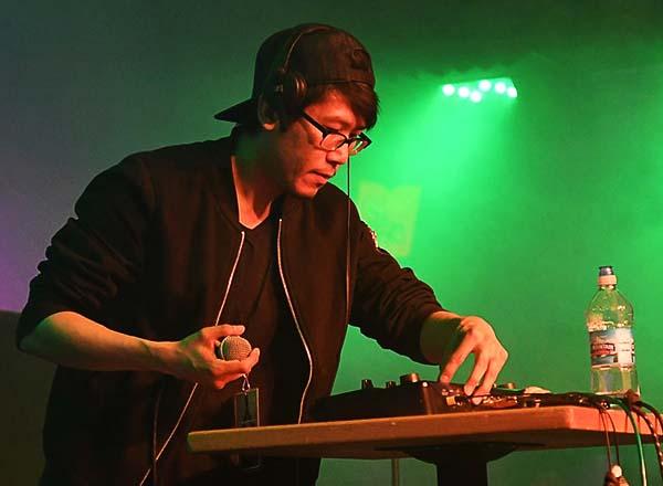 A DJ running a soundboard, with a green background