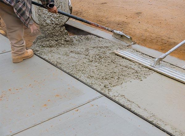 Sidewalk being repaired by a construction worker.