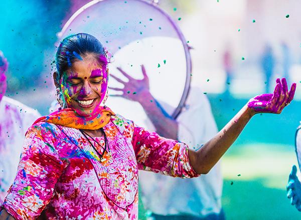 Hindu woman dancing with many colors on her face, clothing, and hair. 