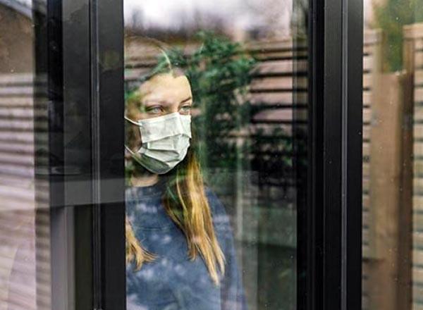 Image for social isolation workshop (woman in a mask staring out a window)