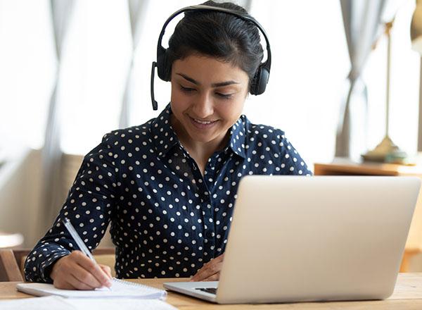 A student takes notes while laptop is open. 