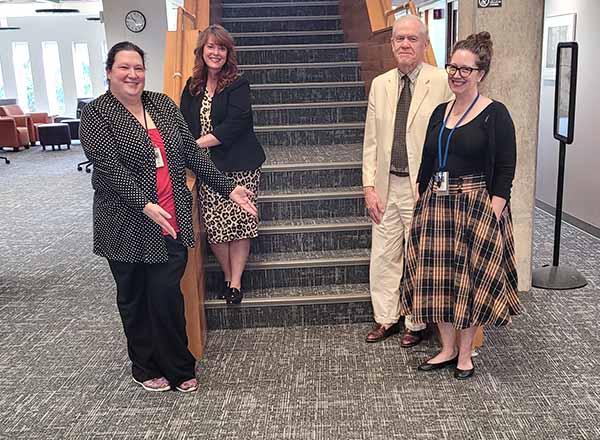Eshleman Library employees standing by stairs showing new carpet.