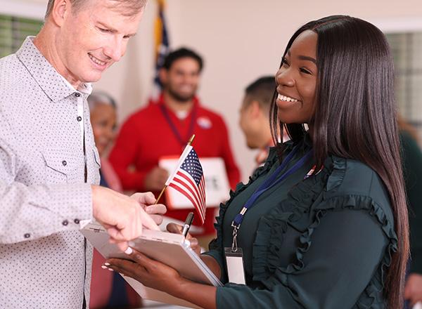 Volunteer works at polling place in the USA election assisting voter with his registration.
