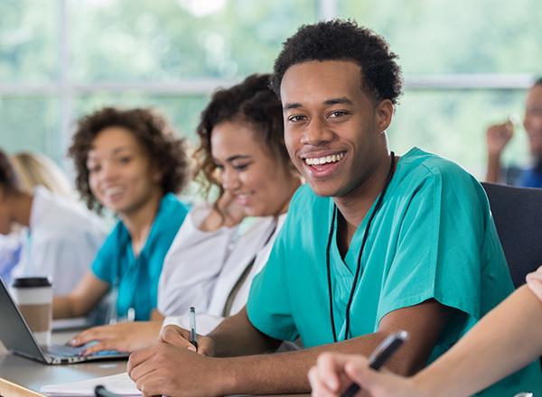 Pre-med students smiling and taking notes in group setting.