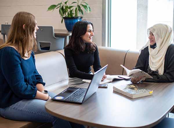 Students talking with each other at a table in the Honors Hub.