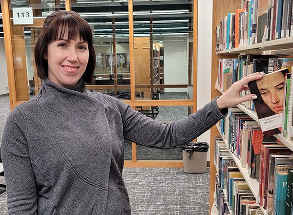A photo of Korinna Kasara pulling a copy of Jayne Eyre from the shelf.