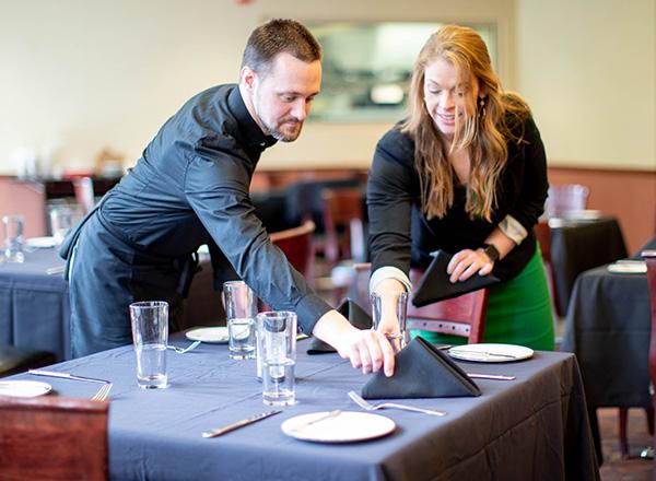 photo of 2 5101 employees setting the table. 