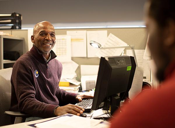 advisor at his computer meets with a student
