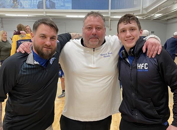 Photo of Coach Derrick Favot, Coach Grant MacKenzie, and Justin Labon at a wrestling meet. 
