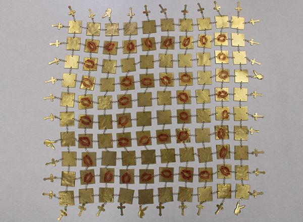 Art made of gold metal squares with red lip prints chained together, adorned with gold metal crosses and Playboy bunnies.