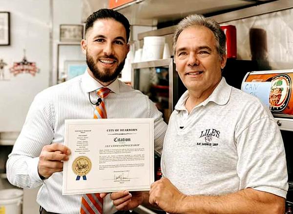 Mayor Abdullah Hammoud presenting Harry Lile with a framed award.