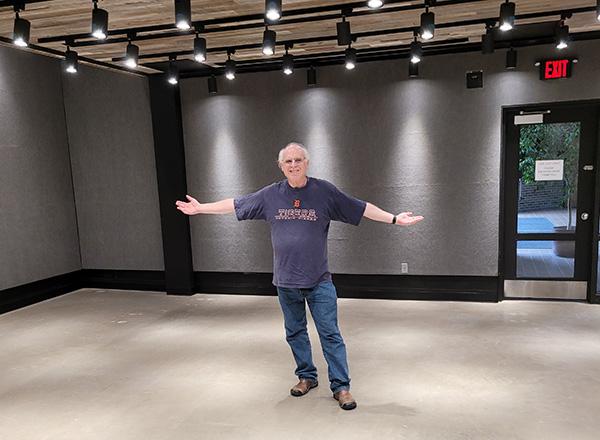 Steve Glazer standing in the middle of the gallery with his arms outstretched.