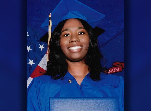 Daisha Griffin in commencement robe and cap with diploma, smiling.