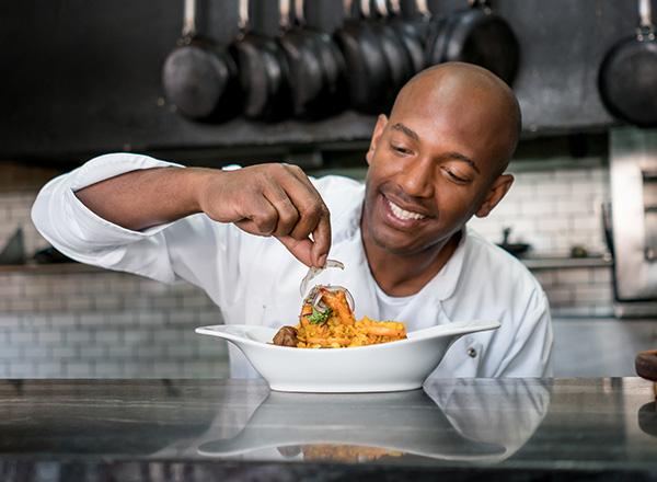 Chef plating food in a restaurant kitchen.