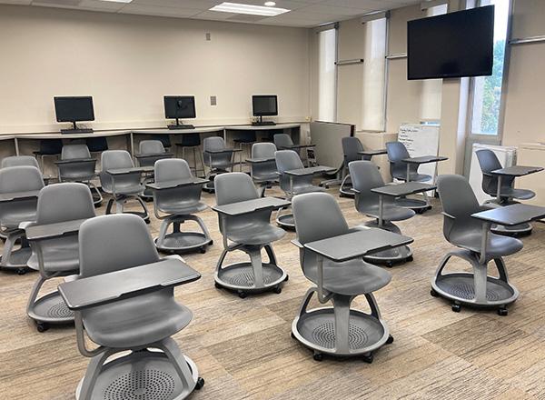 Hyflex classroom in Liberal Arts building with grey desks, computers, and a giant tv screen.