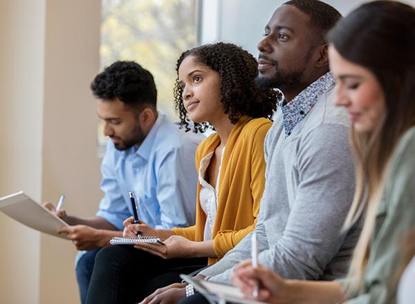 A diverse group of students taking notes during an informational session.