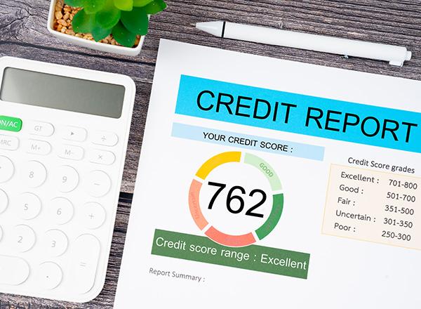 A calculator on a desk next to credit report paperwork and a pen.
