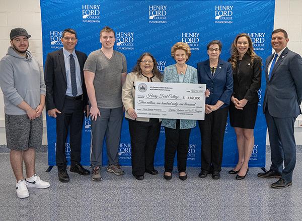 Group of people standing in front of backdrop, displaying an oversize check.