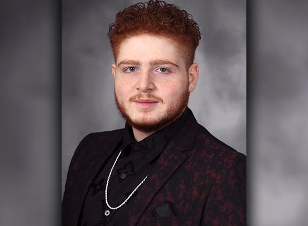 Hilal Baalbak has reddish hair and is wearing a formal outfit with a silver chain.