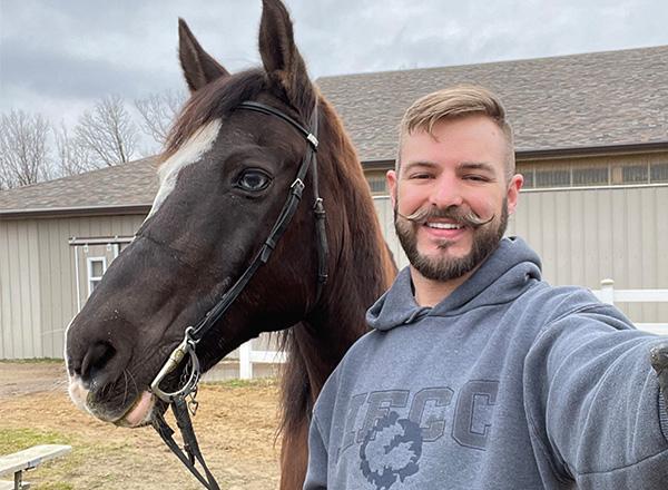 Michelangelo Molinari is wearing a hoodie and taking a selfie with his horse Smoke. 