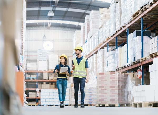 A man and woman walking in a wearhouse looking at the shelves.