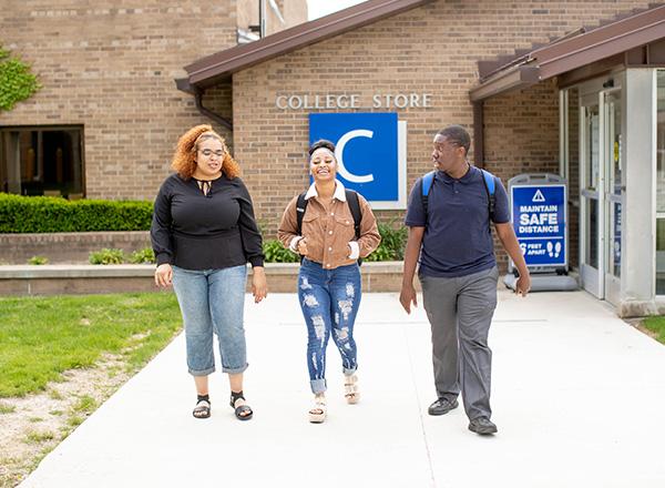 Three HFC students walking out and away from the College Store.