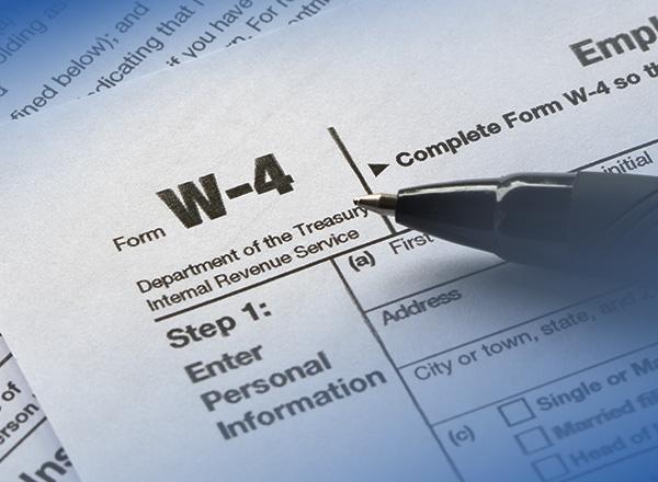 Close-up of a W-4 tax form with a pen over the form.