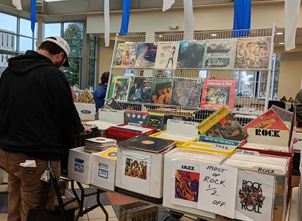 A patron of the WHFR Record Show perusing through one of the record show's collection of vinyl.