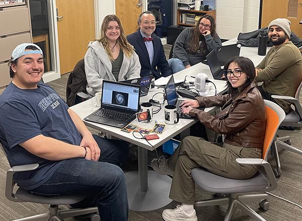 Five students from research group with Jesse Mason sitting around a table.