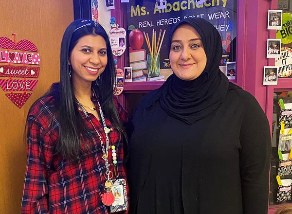 Rana Zeineddine and friend posing and smiling for a picture with school decor in the background. 