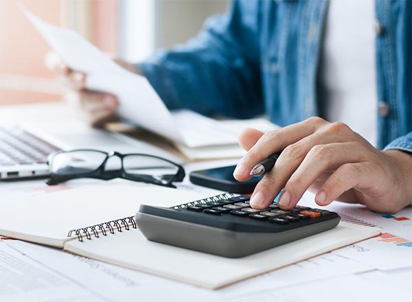Man's hand on calculator with papers in the other hand. 