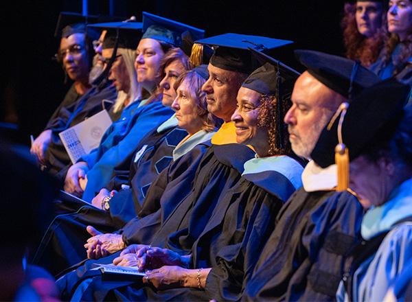 HFC faculty dressed in their regalia on stage