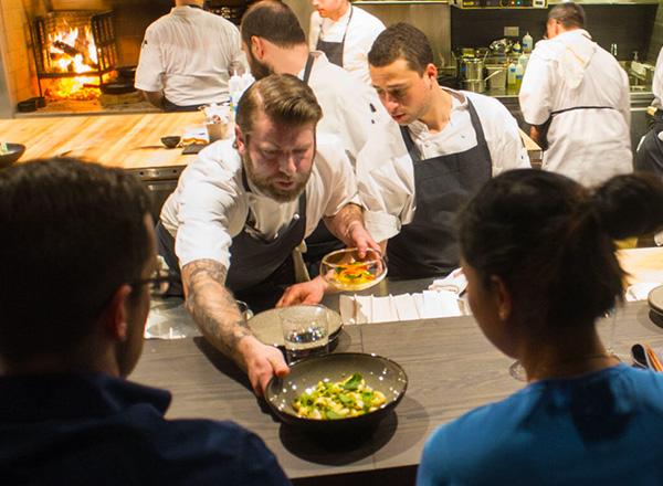 Alinea Group chef serving food.