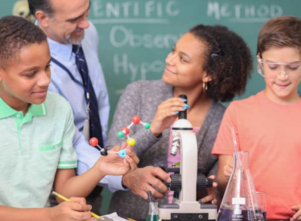 Children exploring different science objects with teacher supervision.