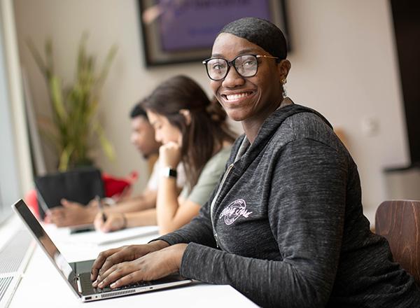 Detroit Promise student working on laptop and smiling.